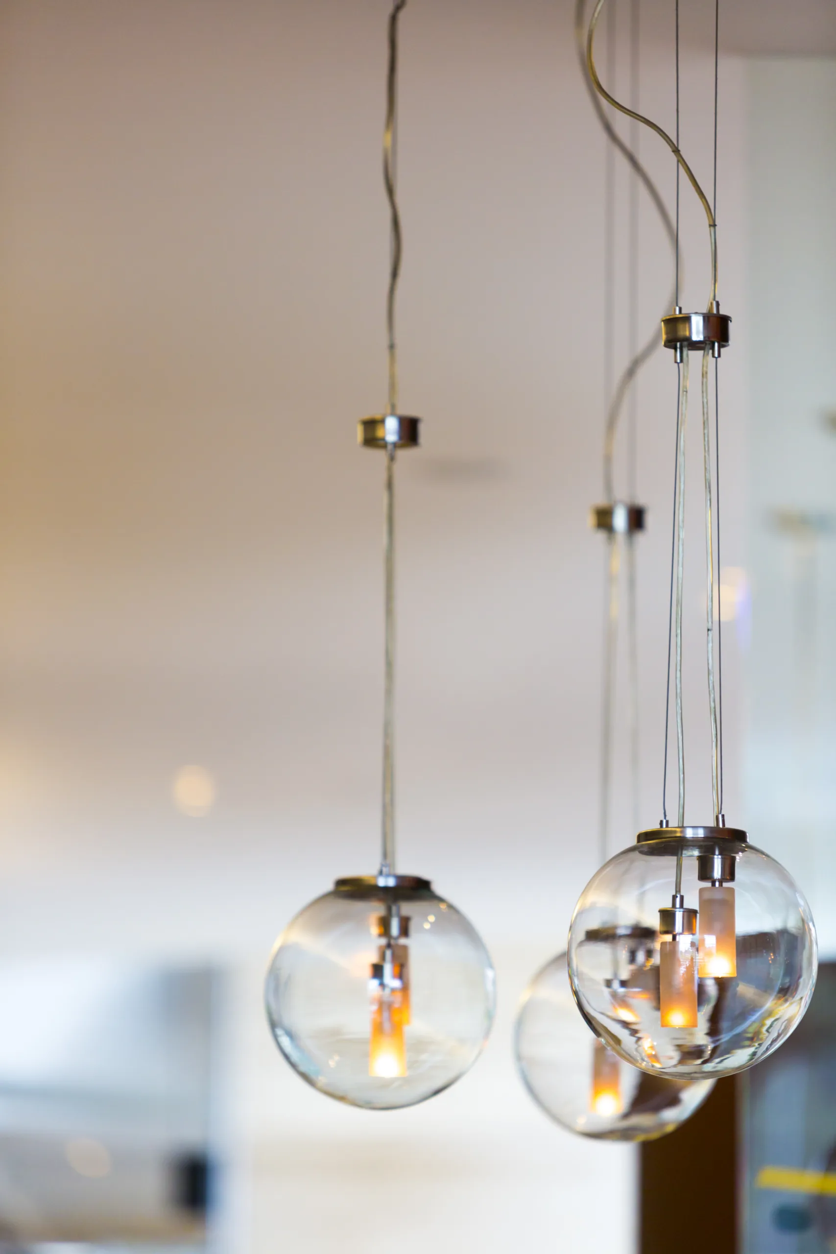 Close-up of modern hanging pendant lights with clear glass globes and exposed filament bulbs, set against a softly blurred background. This elegant lighting creates a warm, inviting ambiance in any space.